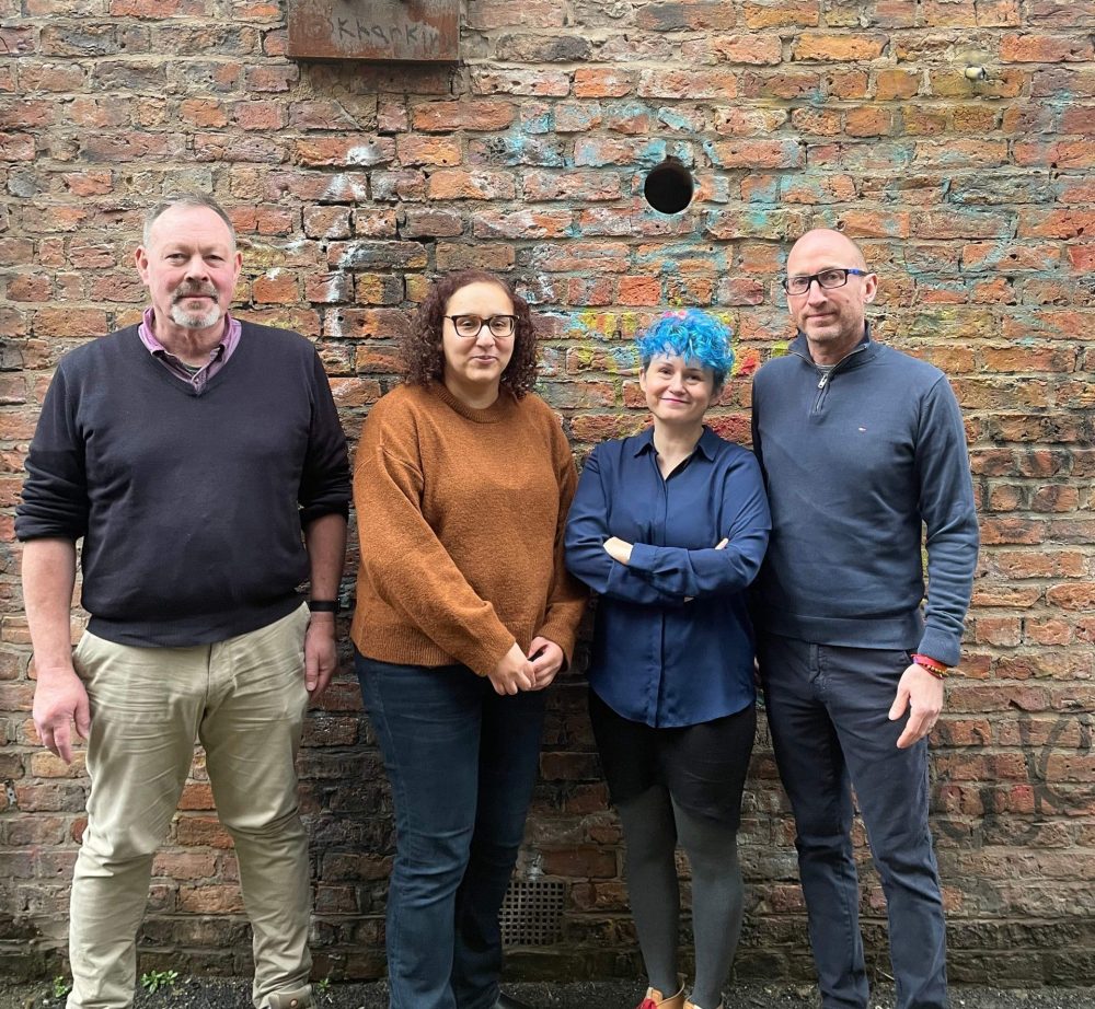 Four of Gaddum's traumatic bereavement therapy team against an industrial brick wall in Manchester